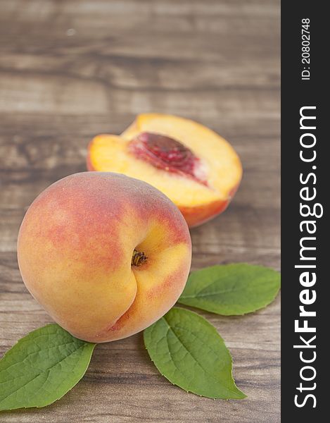 Ripe peach with leaf on wood background