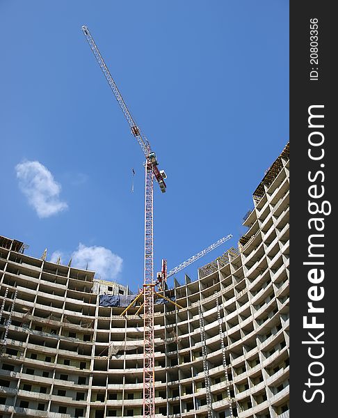 Building crane at the background of a multi-storey building under construction