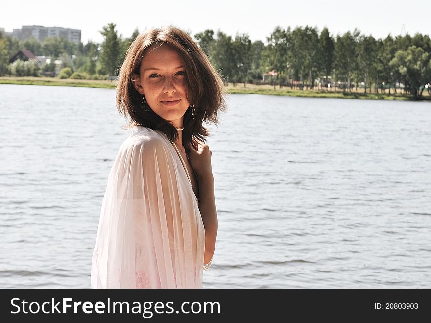 Beautiful girl in a pink dress on river shore