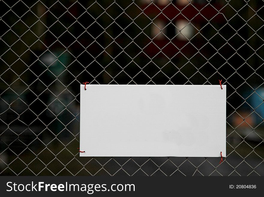 Blank sign attached to metal fence. Blank sign attached to metal fence.