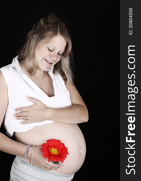 Heavily pregnant blond female against a black background. Heavily pregnant blond female against a black background