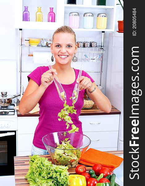 Smiling woman making a fresh salad in the kitchen