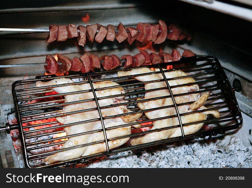 Grilled chicken and kebab getting ready on charcoal fire