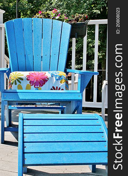 A blue Adirondack chair with foot rest on a white outdoor deck