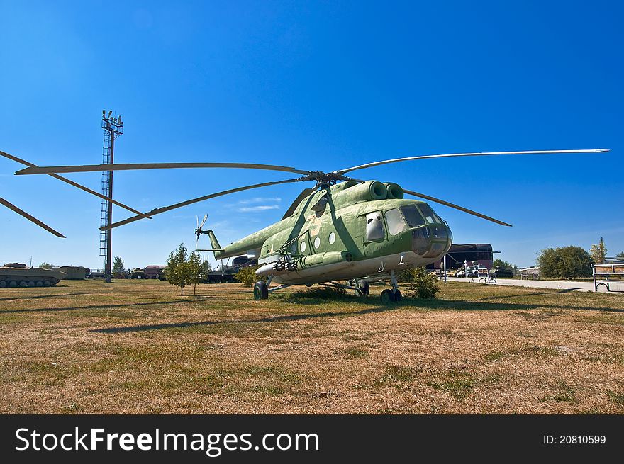 Old Russian helicopter on the grass. Against the background of blue sky.