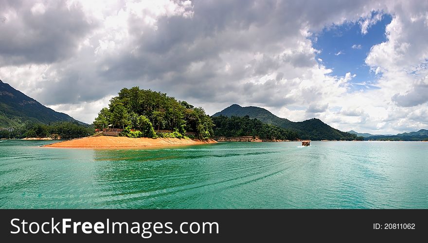 Little boat in the green river with cloudy sky.