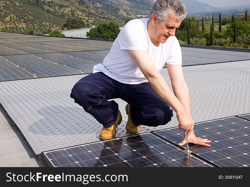 Worker fitting solar panels on a roof. Worker fitting solar panels on a roof