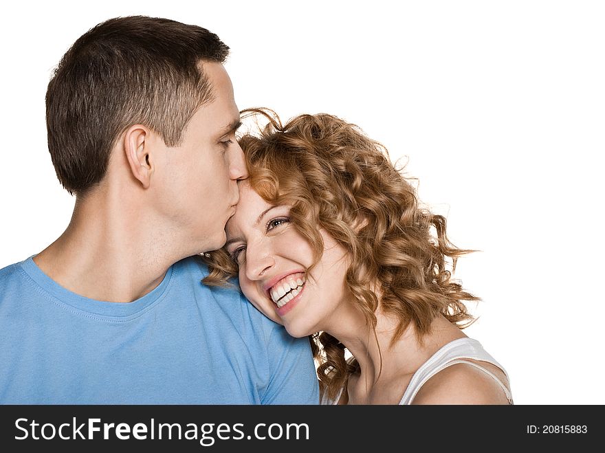 Beautiful young couple kissing against white background