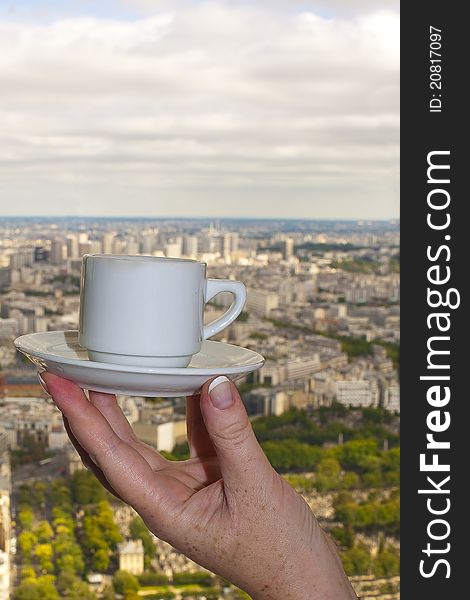 The female hand holds a cup of coffee against Paris from height. The female hand holds a cup of coffee against Paris from height