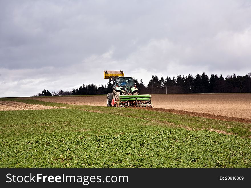 Tractor plowing the acre under dark clouds. Tractor plowing the acre under dark clouds