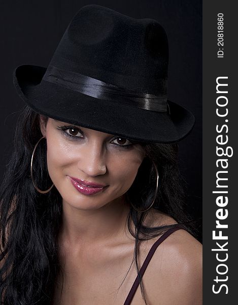 Beautiful brunette with black hat with black background