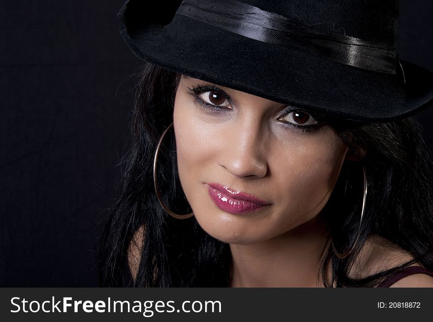 Beautiful brunette with black hat with black background