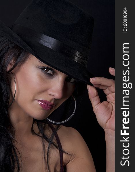 Beautiful brunette with black hat with black background