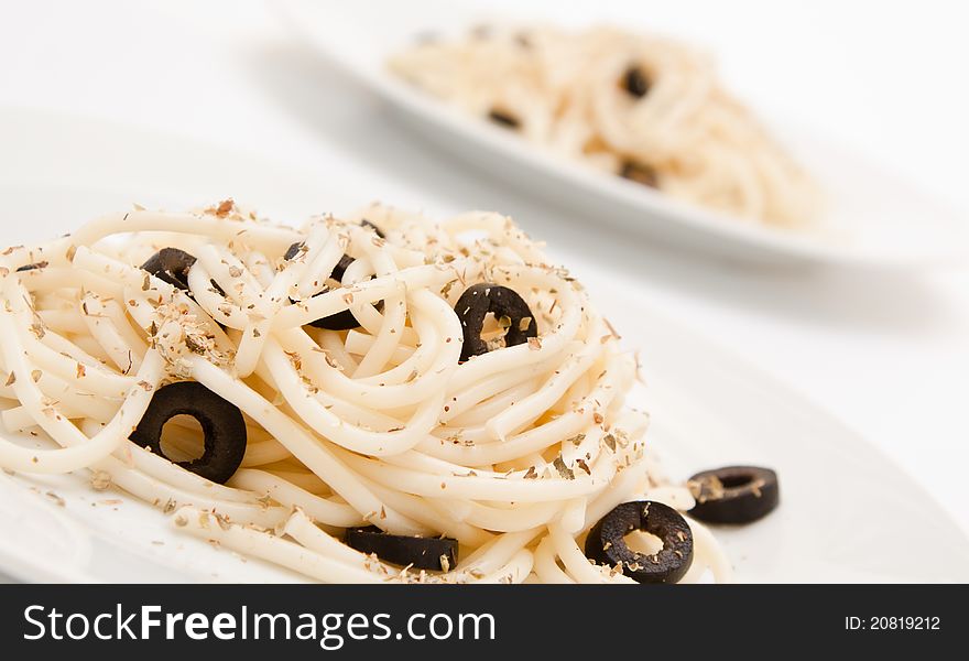Spaghetti with black olives on a white background