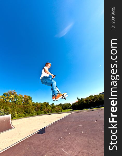 Boy jumping with his scooter at the skatepark