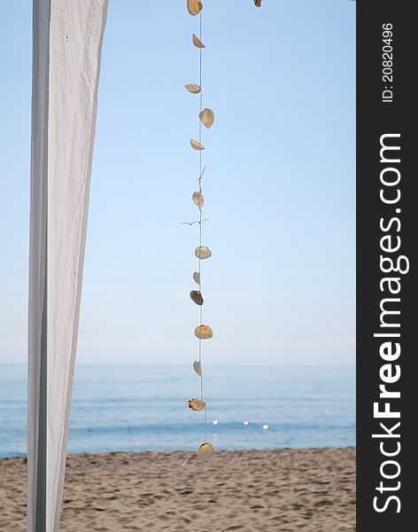 Necklace of shells of mussels, hanging from the tent against the backdrop of beautiful sea. Necklace of shells of mussels, hanging from the tent against the backdrop of beautiful sea