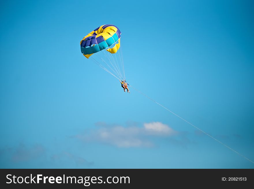 Colorful hang glider in sky over blue sea . Colorful hang glider in sky over blue sea .