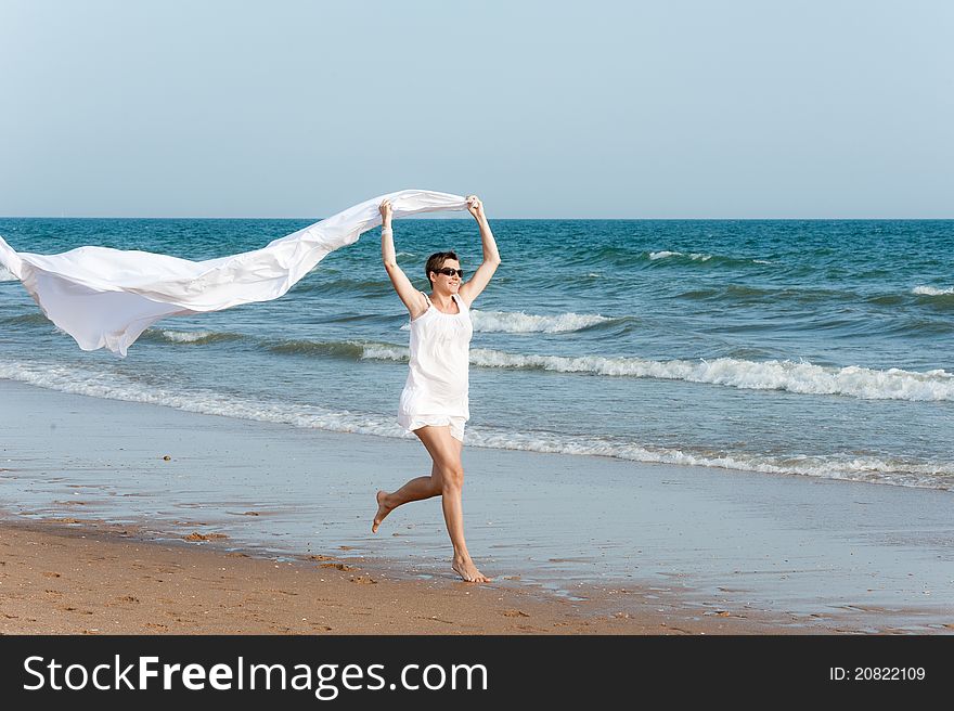 Pregnant woman with white shawl is running on the beach. Pregnant woman with white shawl is running on the beach