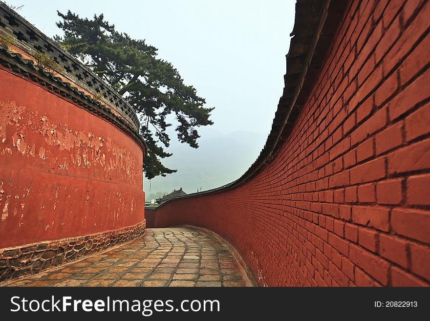 A winding passage flanked by red walls leading to the mount wutai temple in china. A winding passage flanked by red walls leading to the mount wutai temple in china.