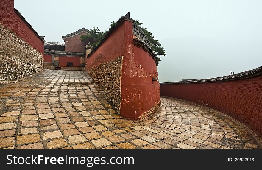 A winding passage flanked by red walls leading to the mount wutai temple in china. A winding passage flanked by red walls leading to the mount wutai temple in china.