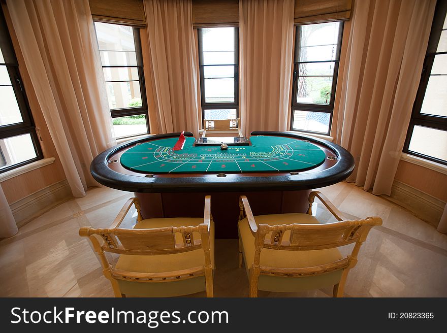 A Gambling table placed in the front of big windows.