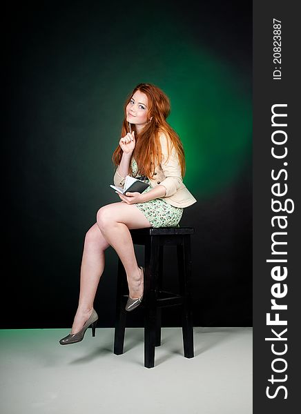 Studio shot of beautiful red haired woman sitting on the chair