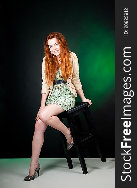 Studio shot of beautiful red haired woman sitting on the chair