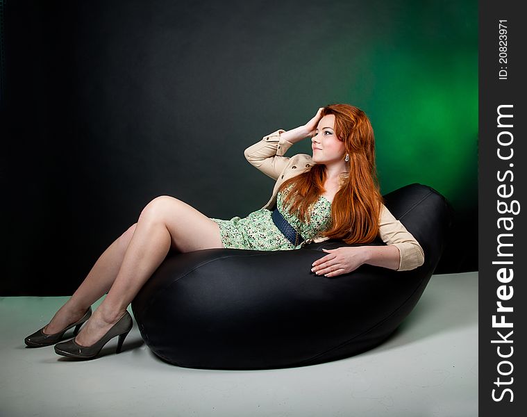 Studio shot of beautiful red haired woman sitting on the chair