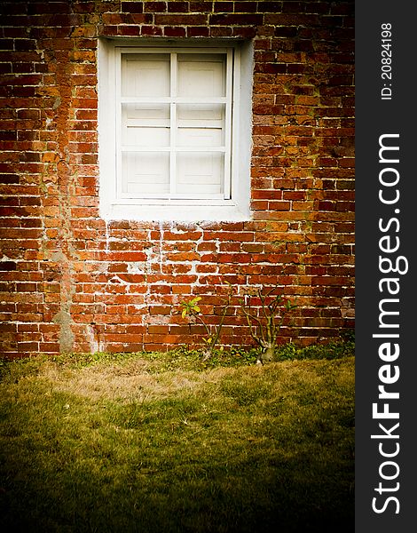 Red brick Wall with white window and grass
