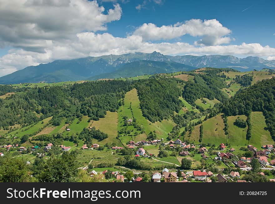 View from above of a village in the Romanian countryside. Mountains and cloudscape in the background. View from above of a village in the Romanian countryside. Mountains and cloudscape in the background