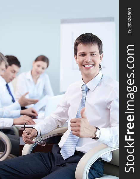 An attractive young man with his thumb up in the office. An attractive young man with his thumb up in the office