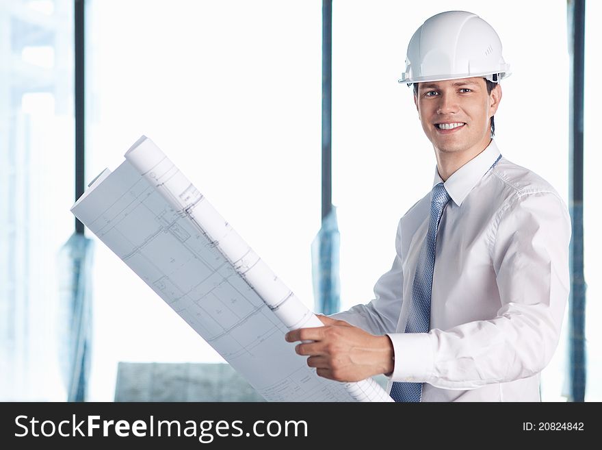 A man in a helmet with a plan for construction. A man in a helmet with a plan for construction