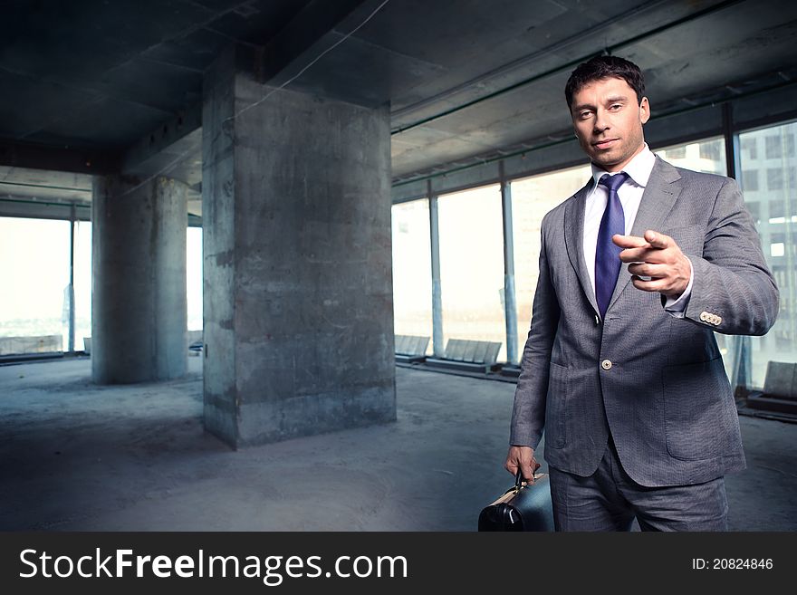 A man in a suit with a briefcase at a construction site. A man in a suit with a briefcase at a construction site