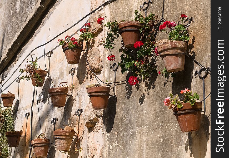 Typical wall planter pots with Geranium hanged on a wall Tuscany Italy style. Typical wall planter pots with Geranium hanged on a wall Tuscany Italy style