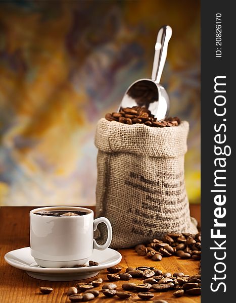 Studio shot composition of cup with coffee and sack with coffee beans