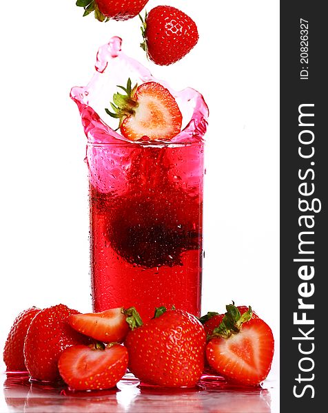 Strawberry falling into the glass with drink and makes big splashes