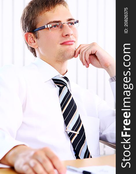 Young businessman thinks about something in his office. Young businessman thinks about something in his office
