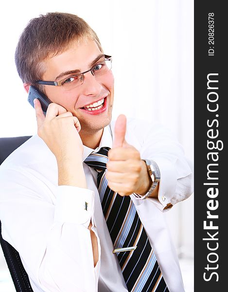 Young Businessman shows OK sign while calling by phone in his office
