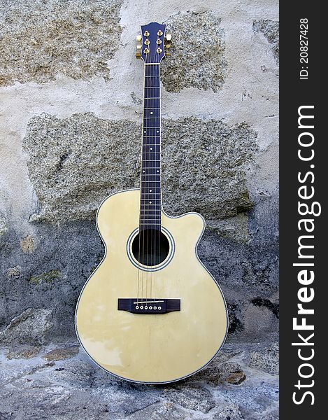 Acoustic guitar leaning against a stone wall with great colors