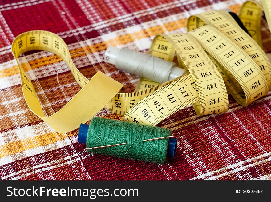 Four coils with strings and a centimetric tape on a checkered fabric. Four coils with strings and a centimetric tape on a checkered fabric