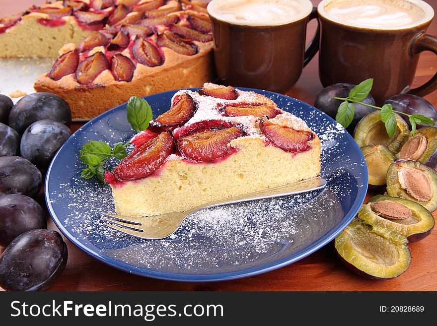 Plum pie, coffee and plums deocrated with mint on a wooden background. Plum pie, coffee and plums deocrated with mint on a wooden background