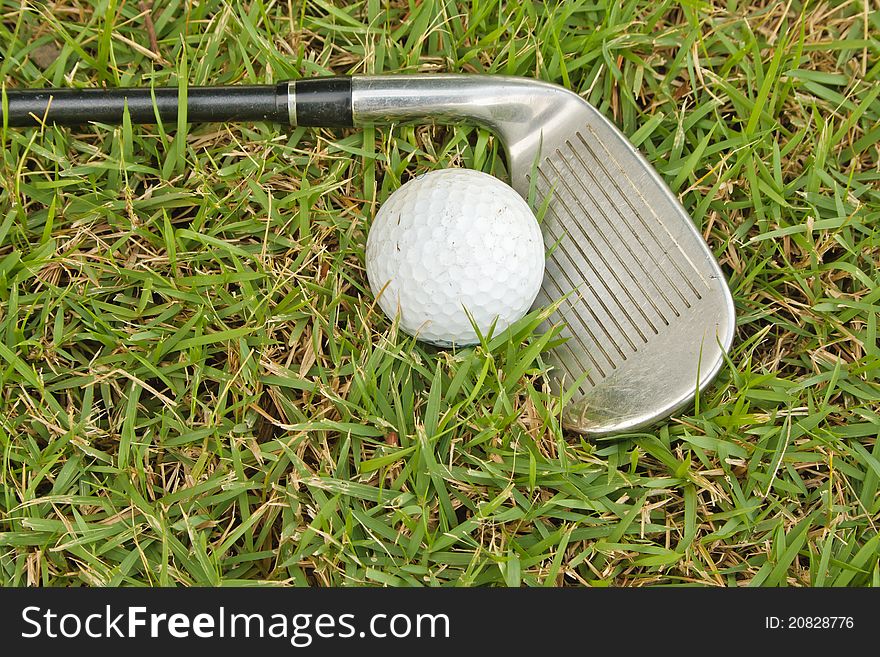 Golf club and one ball on grass