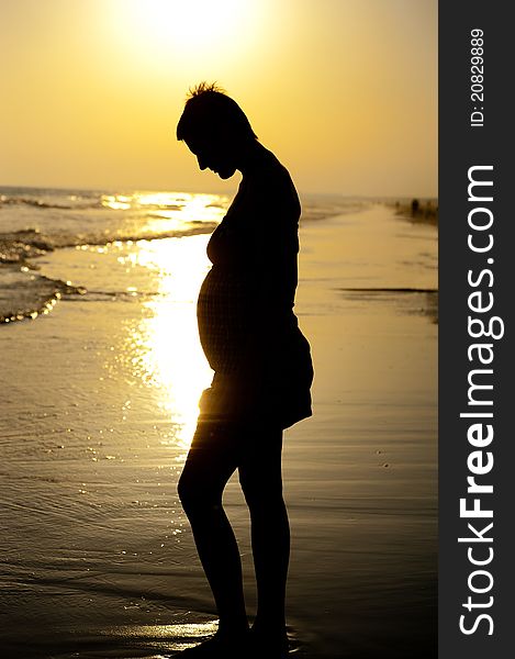 Pregnant woman with background light on the beach