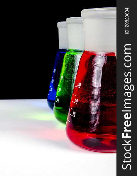 3 colors chemicals in laboratory glassware in a row - Close up on black background. 3 colors chemicals in laboratory glassware in a row - Close up on black background