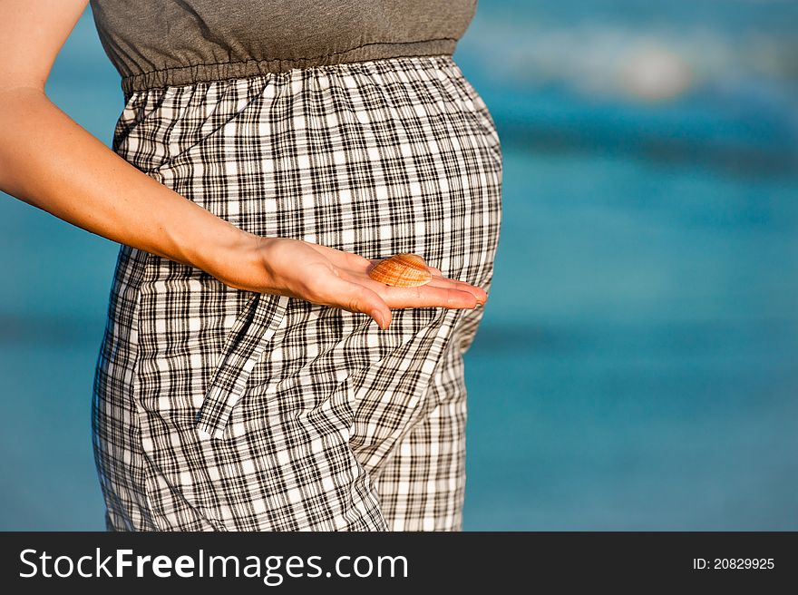 Pregnant woman and ocean in background. Pregnant woman and ocean in background