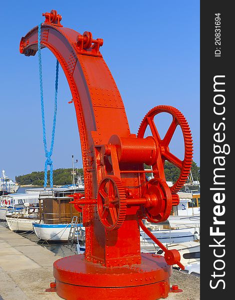 Little red crane for lifting vessels in port