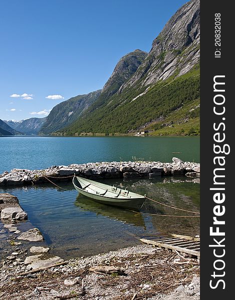 A Norwegian landscape, a fjord, a little dock and a boat parked in it. Norway, Sogn & Fjordane county. Fjord landscape. A Norwegian landscape, a fjord, a little dock and a boat parked in it. Norway, Sogn & Fjordane county. Fjord landscape.