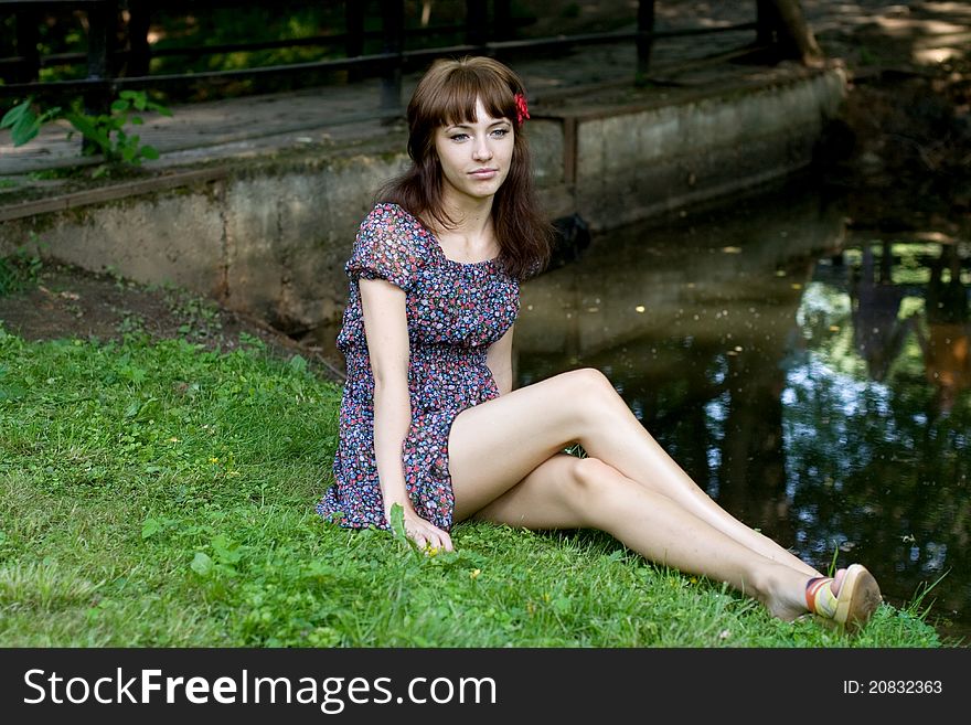 Beautiful girl sitting on bank of a river in summer