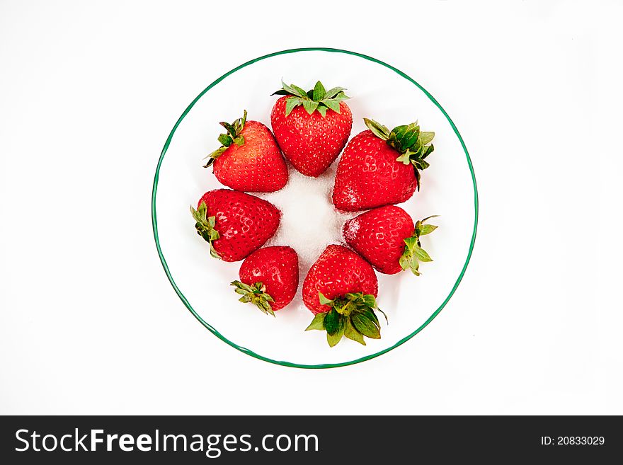 Seven strawberries on a plate with sugar in the center of the plate. Seven strawberries on a plate with sugar in the center of the plate.