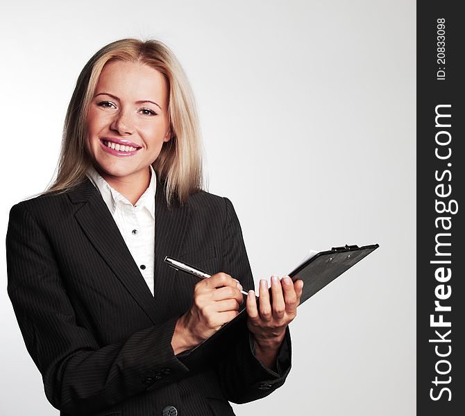 Business woman writing in notebook on a gray background